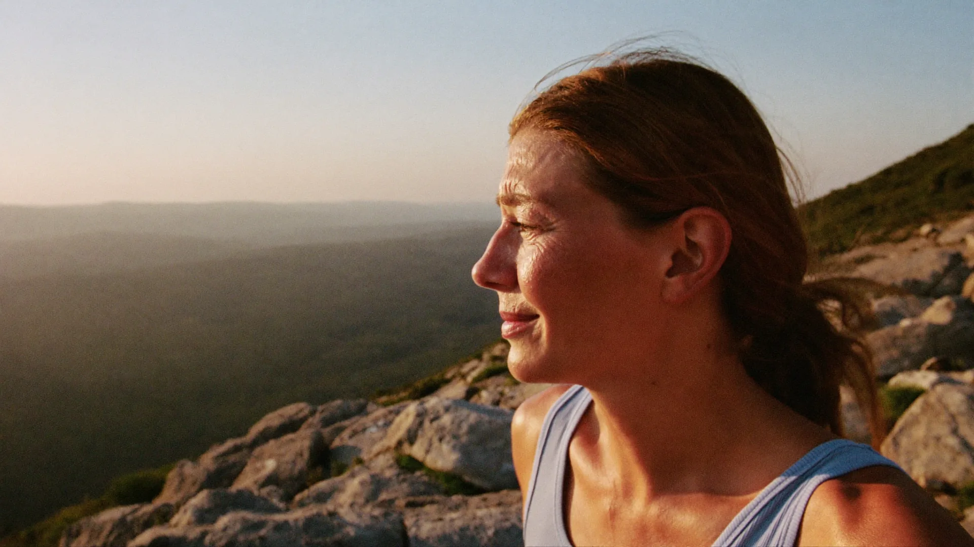 A woman in her forties hiking up a mountain ridge at golden hour